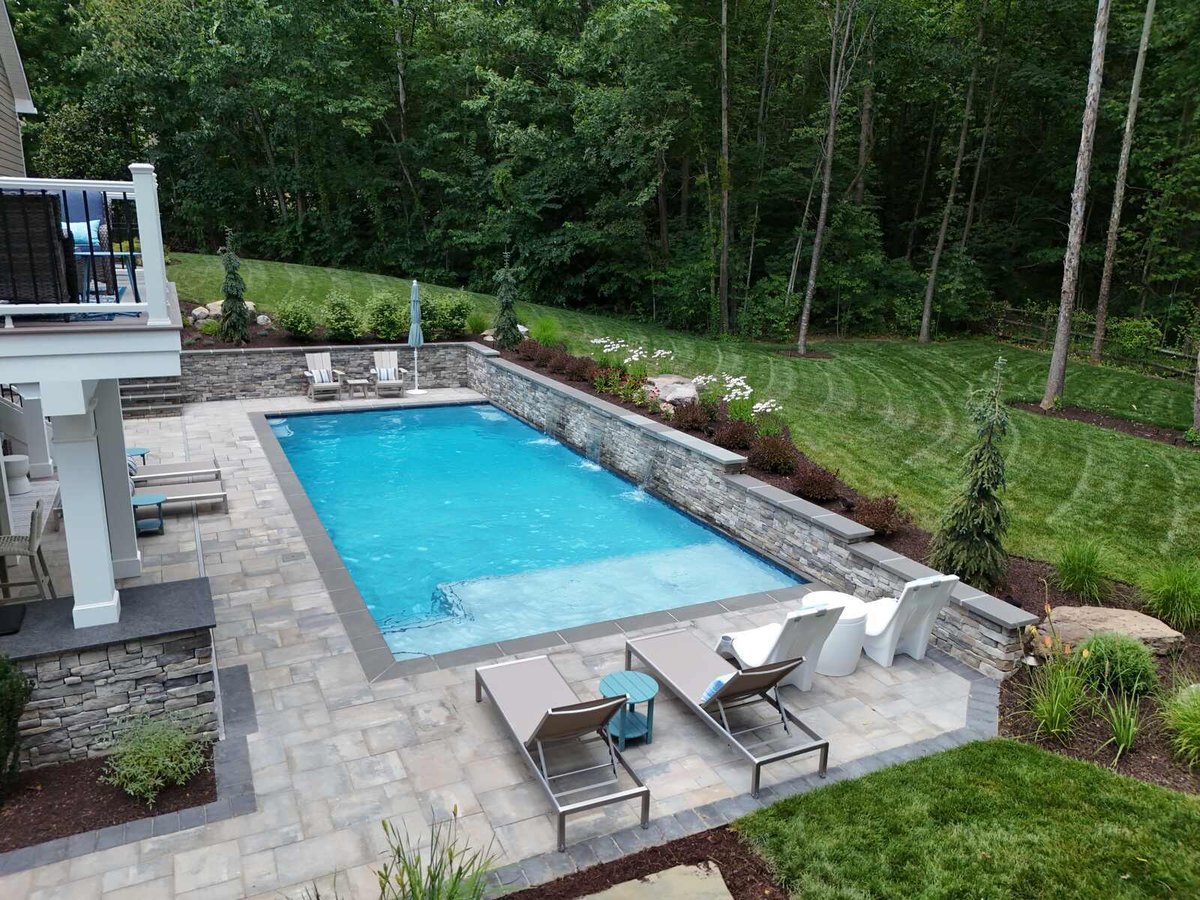 Elevated view of a luxury pool with lounge chairs and stonework, completed by Deckscapes of Virginia in Northern Virginia