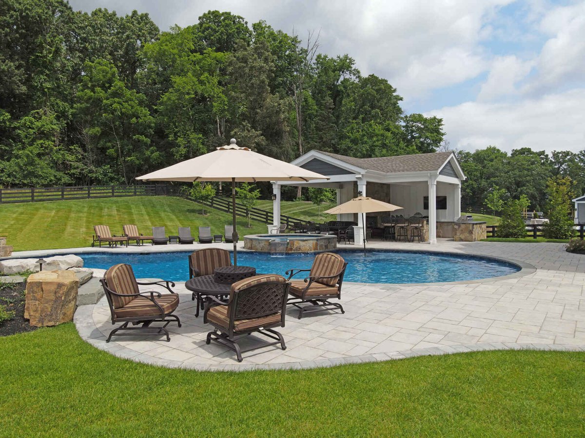 Luxurious backyard pool with seating and umbrellas, designed by Deckscapes of Virginia