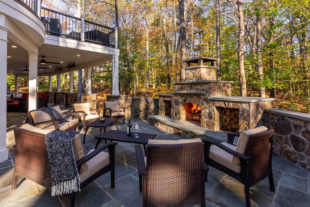 Outdoor living area with stone fireplace and cozy seating by Deckscapes of Virginia in Northern Virginia